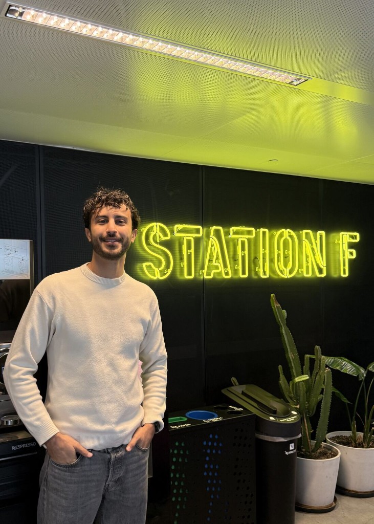 Romain devant l'enseigne lumineuse Station F