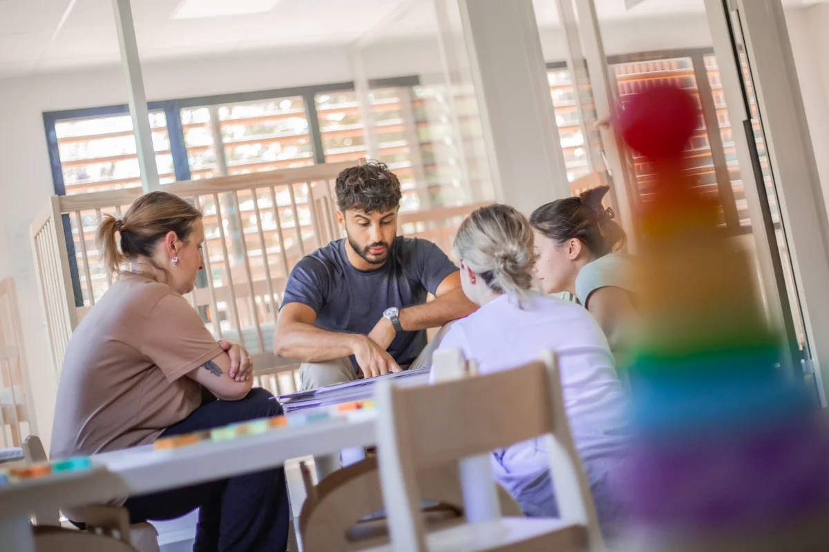 Romain avec les référentes techniques, autour d'une table en crèche