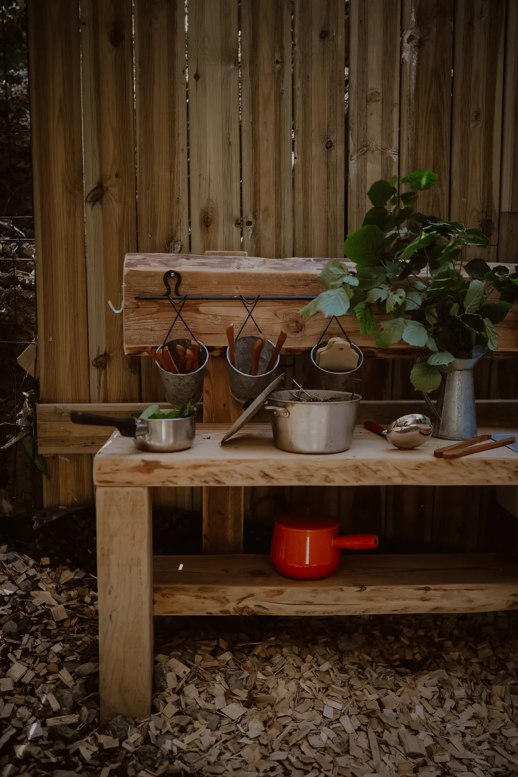 Une cuisine de boue en bois avec casseroles et ustensiles, dehors
