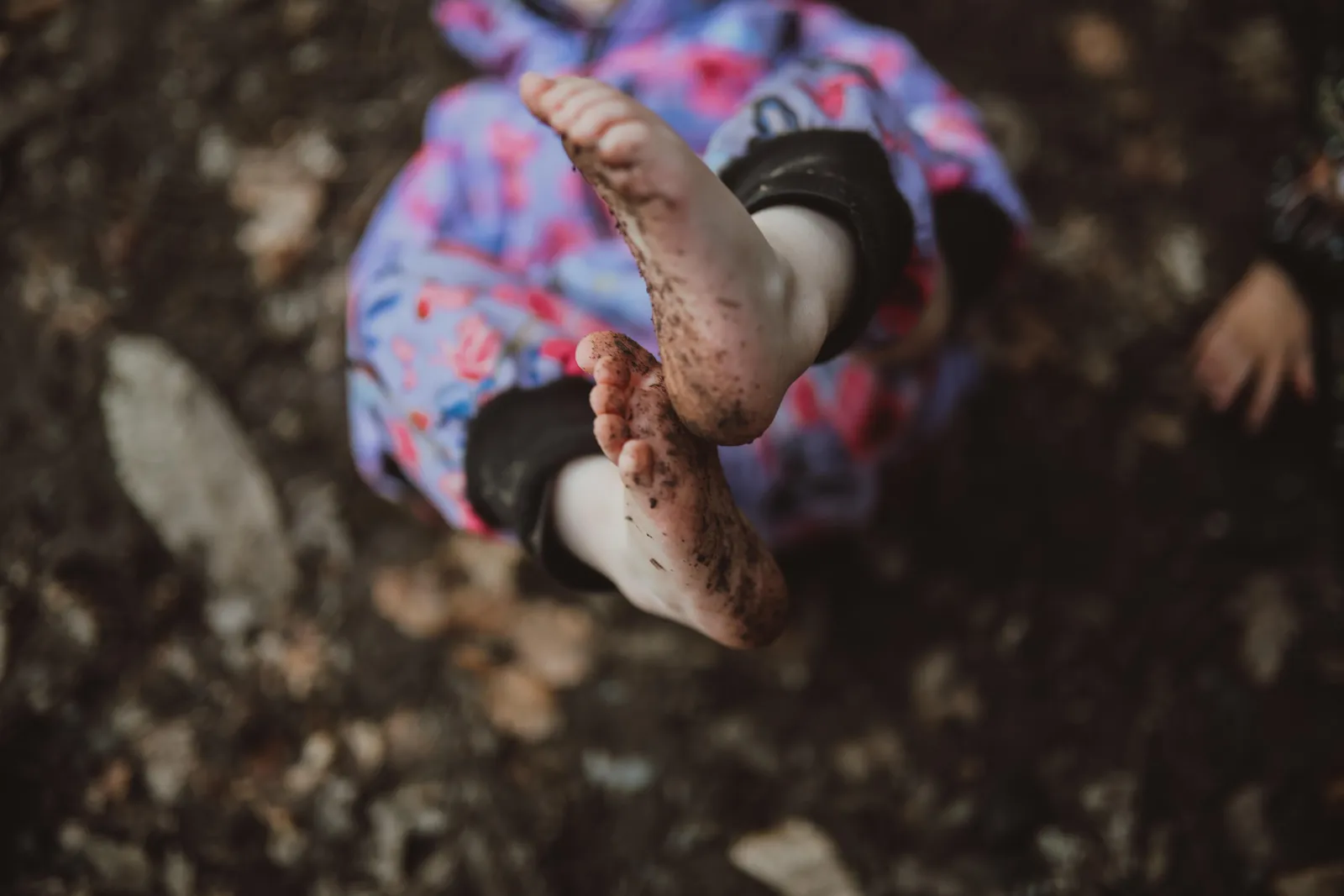 Les pieds nus et boueux d'un enfant assis par terre
