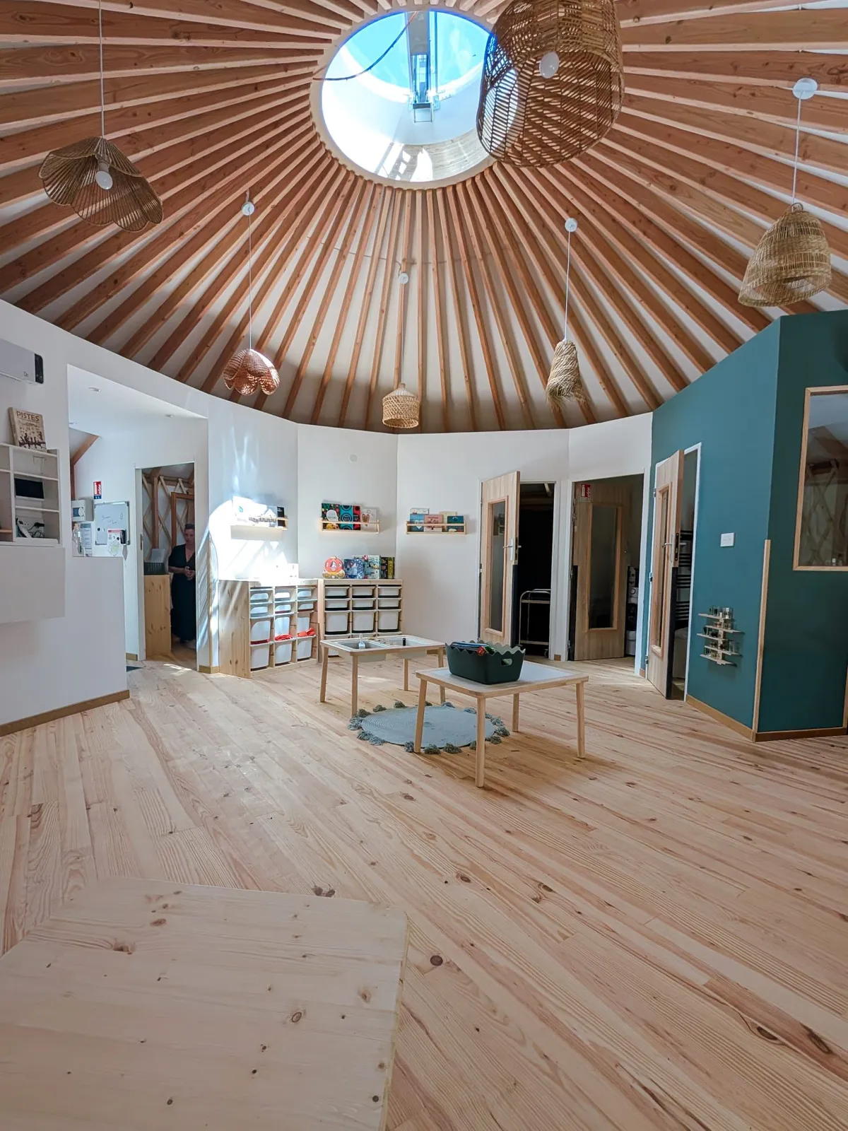 L'intérieur de la yourte : plancher bois, puits de lumière, meubles de rangement bas